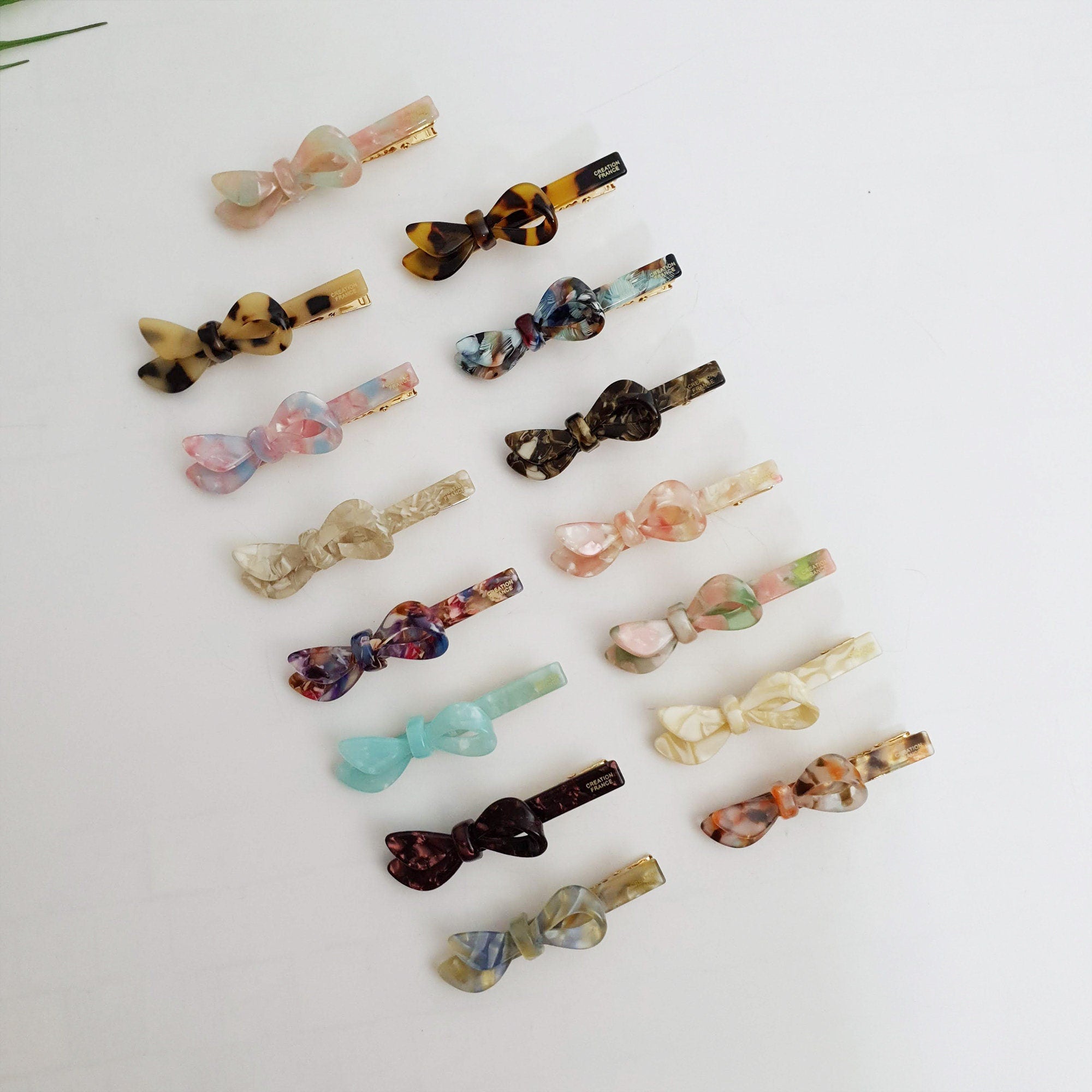 Long cellulose acetate alligator hair clip with a modern asymmetric loop design. Sleek beak clip in tortoise shell and marble patterns for side swept hairstyles.