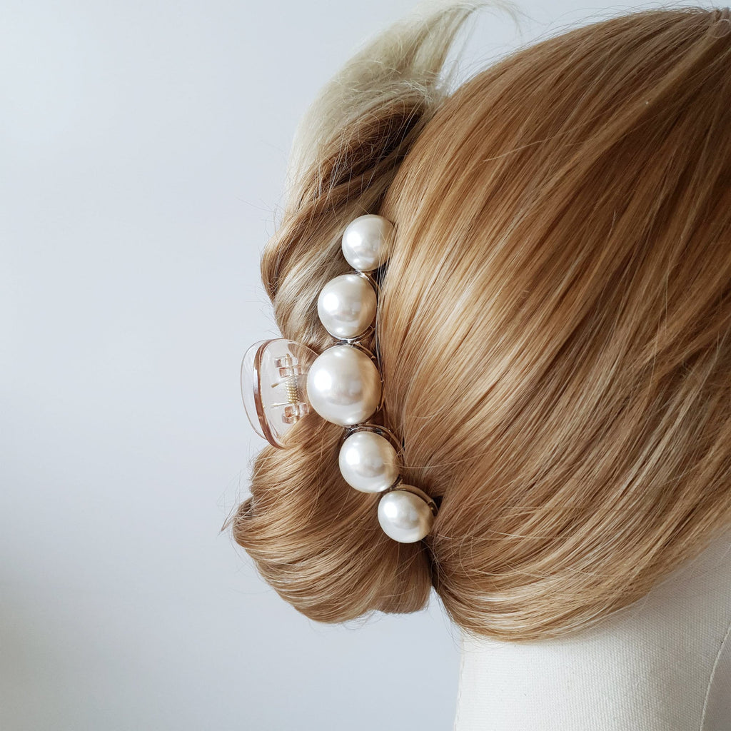 Large faux pearl curved jaw clamp in clear or black base, elegant bridal headpiece for updo styling, wedding guest accessory. A clear plastic hair clip with a row of pearl-like beads. The beads are white and have a slight iridescent sheen. The clip is designed to hold hair in place.
