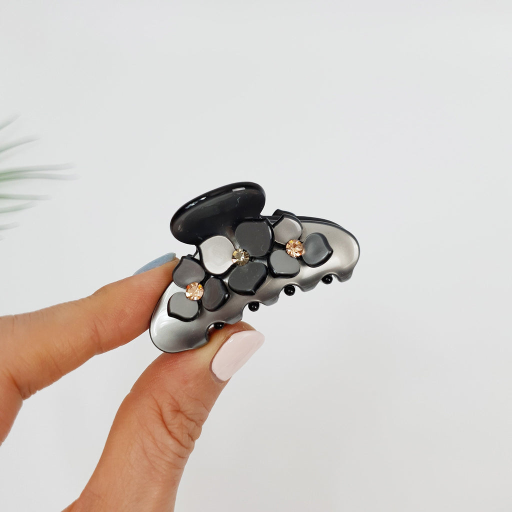 Small cellulose acetate flower hair claw with rhinestone accents. Pastel floral hair clip for half up hairstyles. Cute Korean accessories gift. A black and silver hair claw with a floral design. The claw has a silver base with black accents and is decorated with white, gray, and black flowers with small rhinestones in the center of each flower.