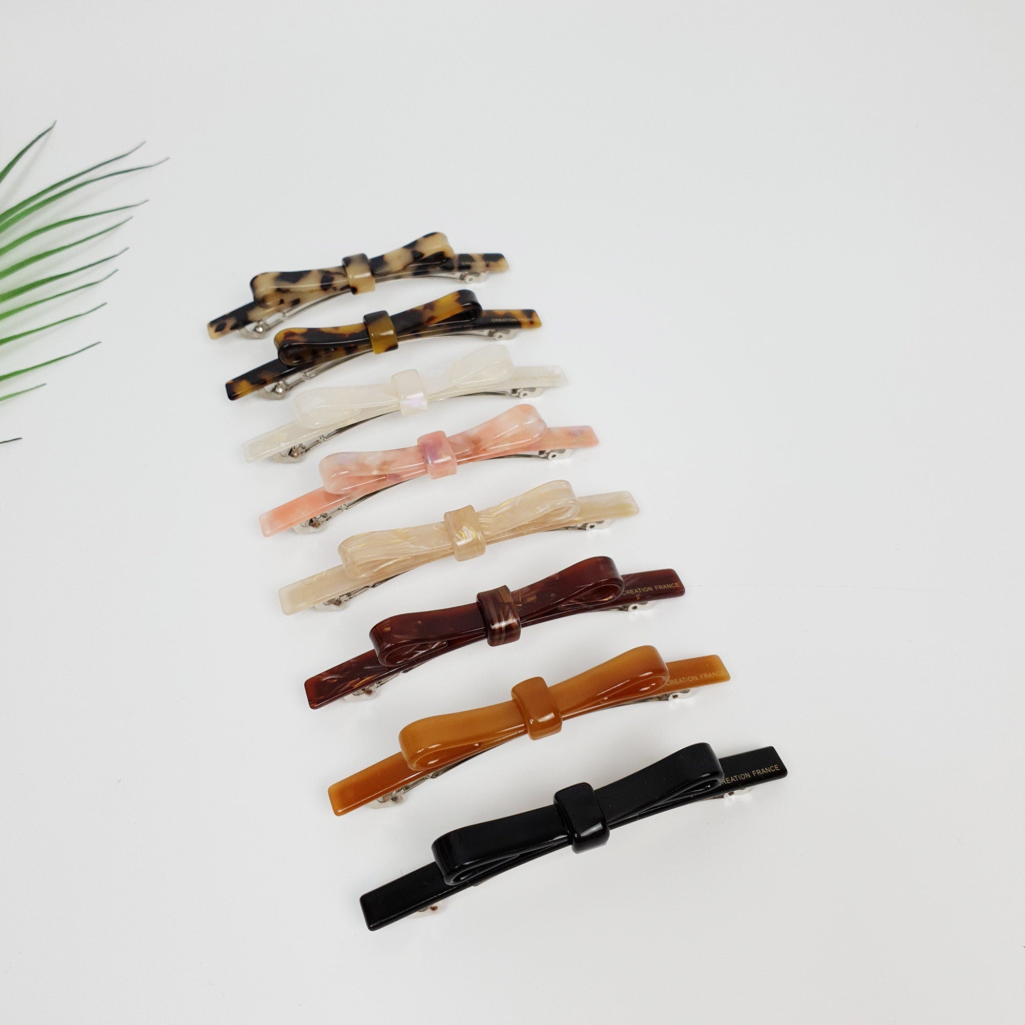 Long cellulose acetate skinny barrette with a small center bow knot. 4.1 inch glossy tortoise shell and marble pattern automatic clip for ponytails or French twists.