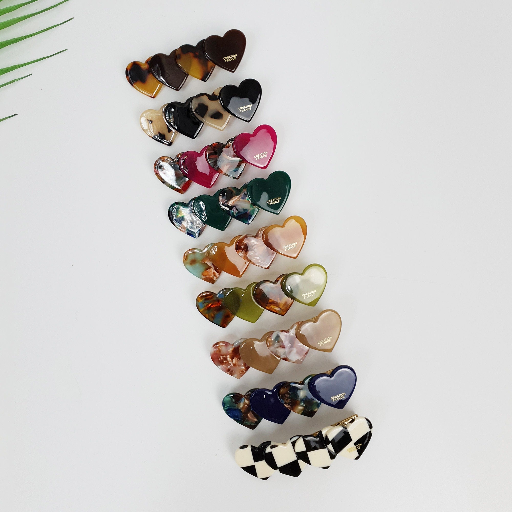 Cellulose acetate side hair clip featuring a row of four overlapping hearts. 2.7 inch tortoise shell and solid color alligator clamp for bangs.