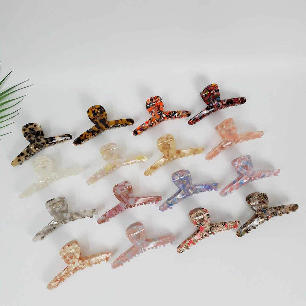 Cellulose acetate large twisted hair claw clip in tortoise shell and marble patterns, big size hair catch for thick hair updo styling. A collection of 17 colorful hair clips with various patterns. The clips are made of plastic and have a claw shape. The colors include brown, black, white, orange, pink, blue, and green.