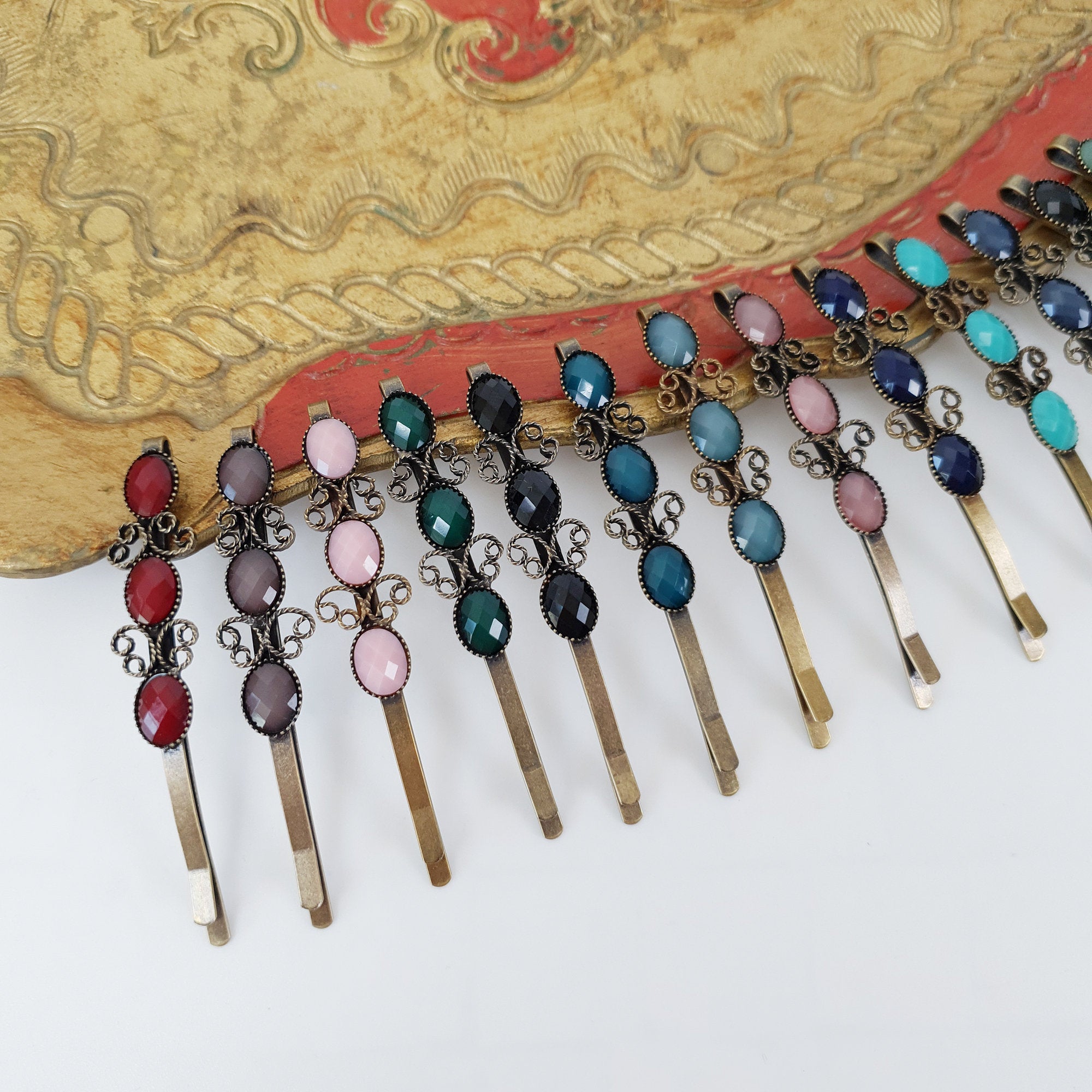 Antique bronze bobby pins featuring three oval cabochon stones and delicate butterfly filigree details. Vintage style hair slides available in 17 colors like turquoise, pearl, and ruby red for side bangs.