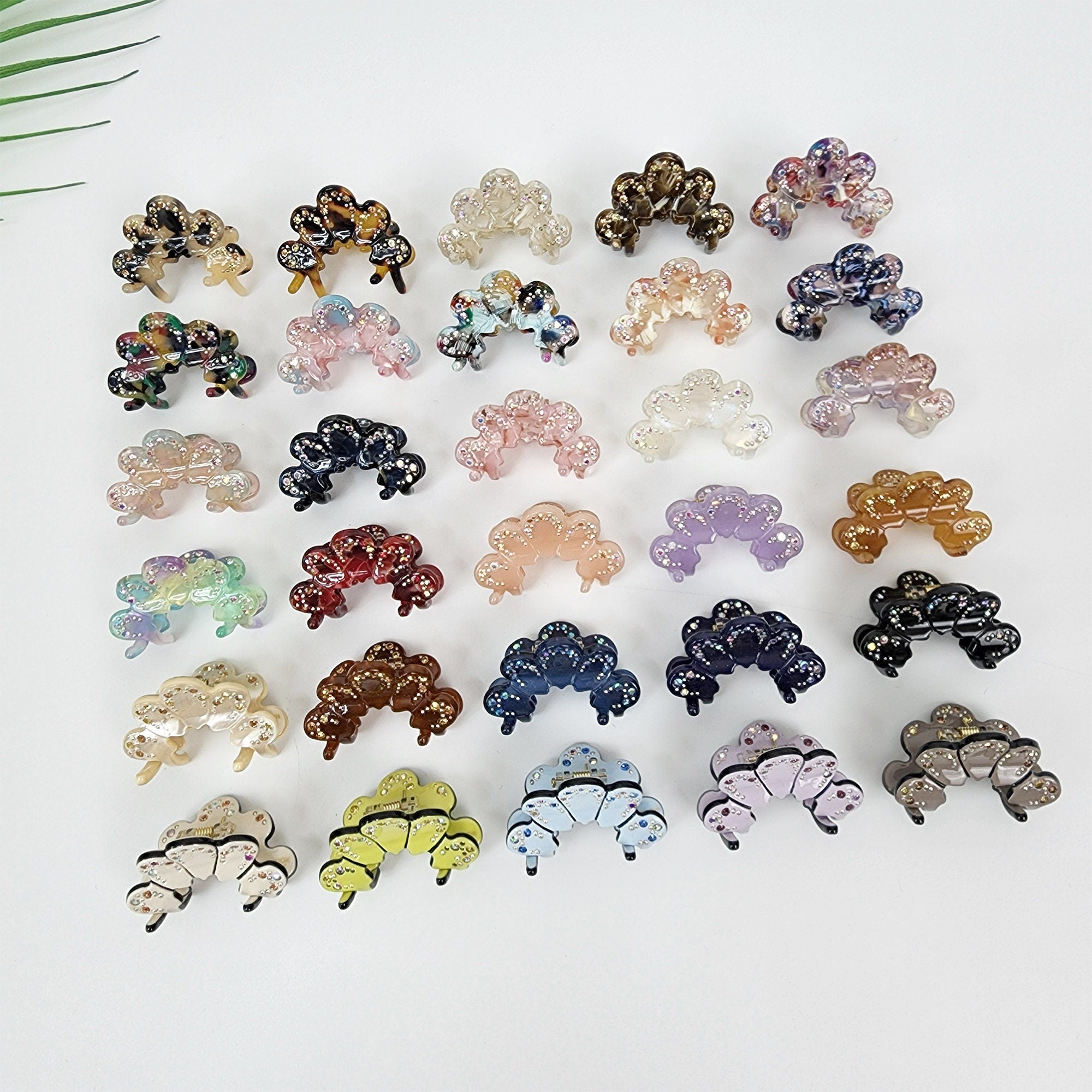 Small cellulose acetate hair claw shaped like a crown with rhinestone crystal accents. Mini tortoise shell and marble pattern jaw clip for side bangs.