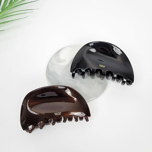 Glossy cellulose acetate pebble hair claw in black and brown, minimalist curved jaw clip for half updo styling, sturdy elegant hair accessories for women.