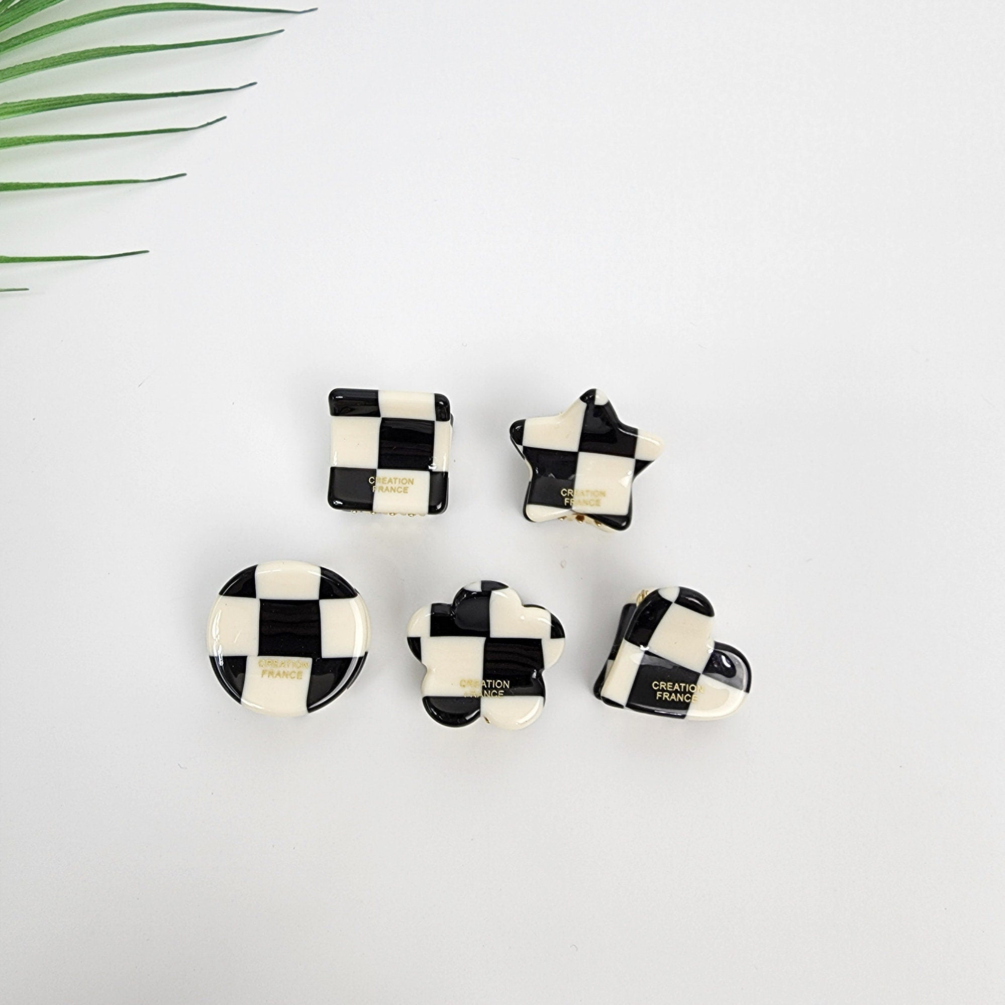 Cellulose acetate mini hair claw clip in black and white checkerboard pattern, geometric small hair clamp for bangs, Mod style cute accessories.  Five black and white checkered hair clips in different shapes: square, star, circle, flower, and heart. Each clip has the words 'CREATION FRANCE' printed on the back.