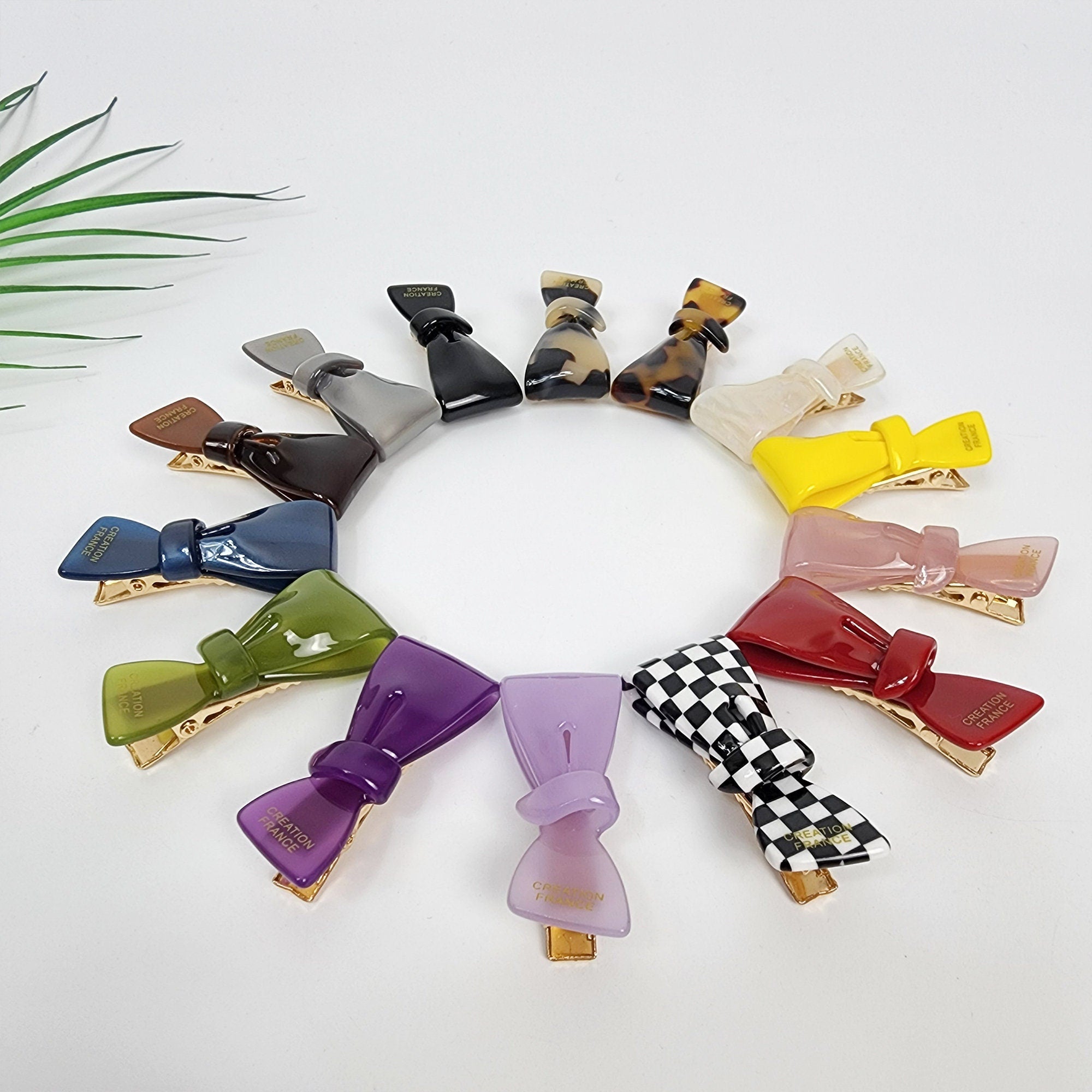 Small cellulose acetate bow hair clip with gold alligator clasp, minimalist side barrette for bangs, toddlers, or thin hair styling. A collection of 14 colorful hair clips with a bow design. The clips are made of plastic and have a gold metal clasp. The clips are arranged in a circle on a white background. The clips are in various colors, including green, purple, red, yellow, pink, and black and white checkered.