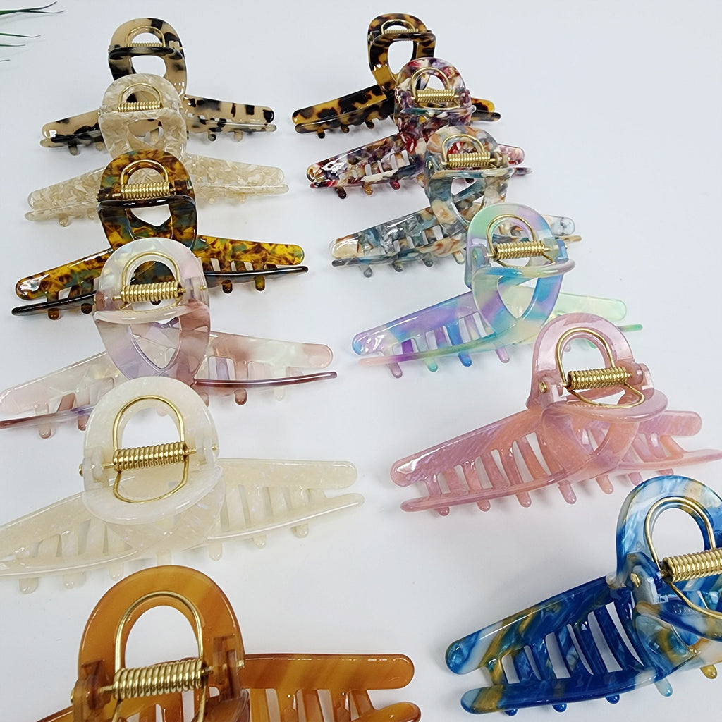 Large cellulose acetate hair claw with unique U-spring mechanism, twisted design in tortoise shell and marble for secure updos.