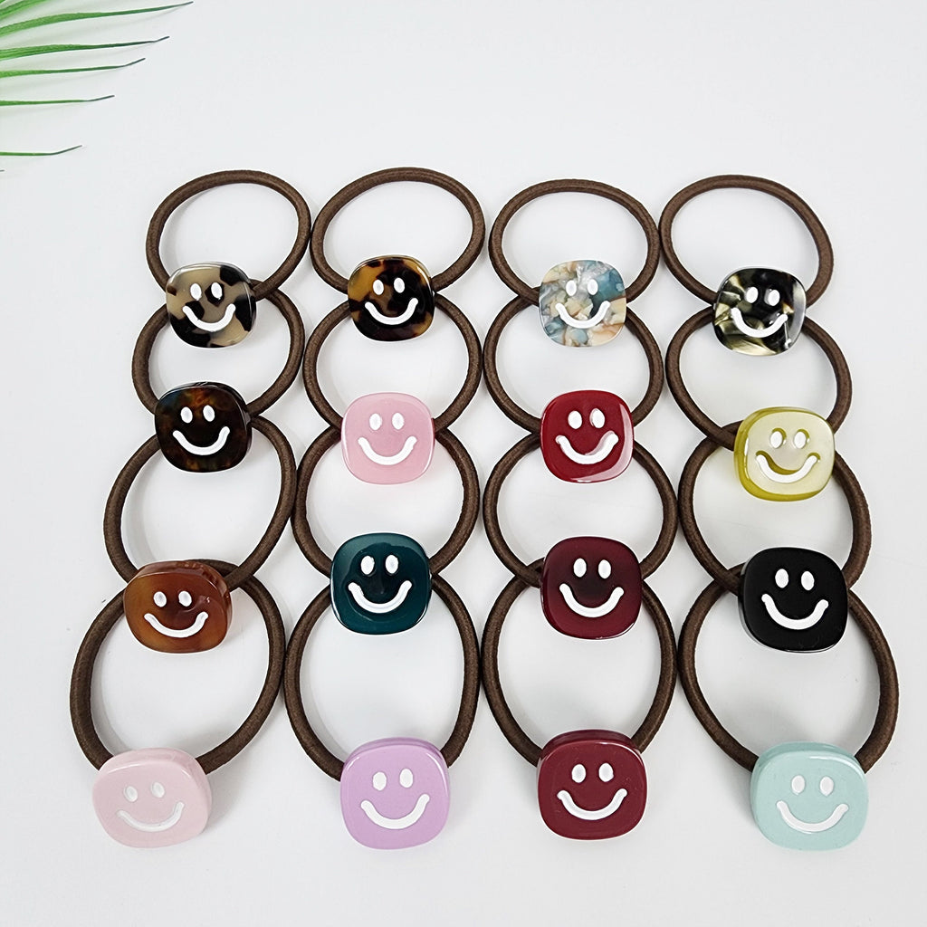Cellulose Acetate Smiley Face Hair Tie, Cute Square Ponytail Holder, Korean Hair Accessories for Girls Birthday Gift, Tortoise Shell Pattern. A collection of brown hair ties with colorful smiley face charms. The charms are in various colors including red, blue, green, pink, and yellow. The charms are made of plastic and have a glossy finish.