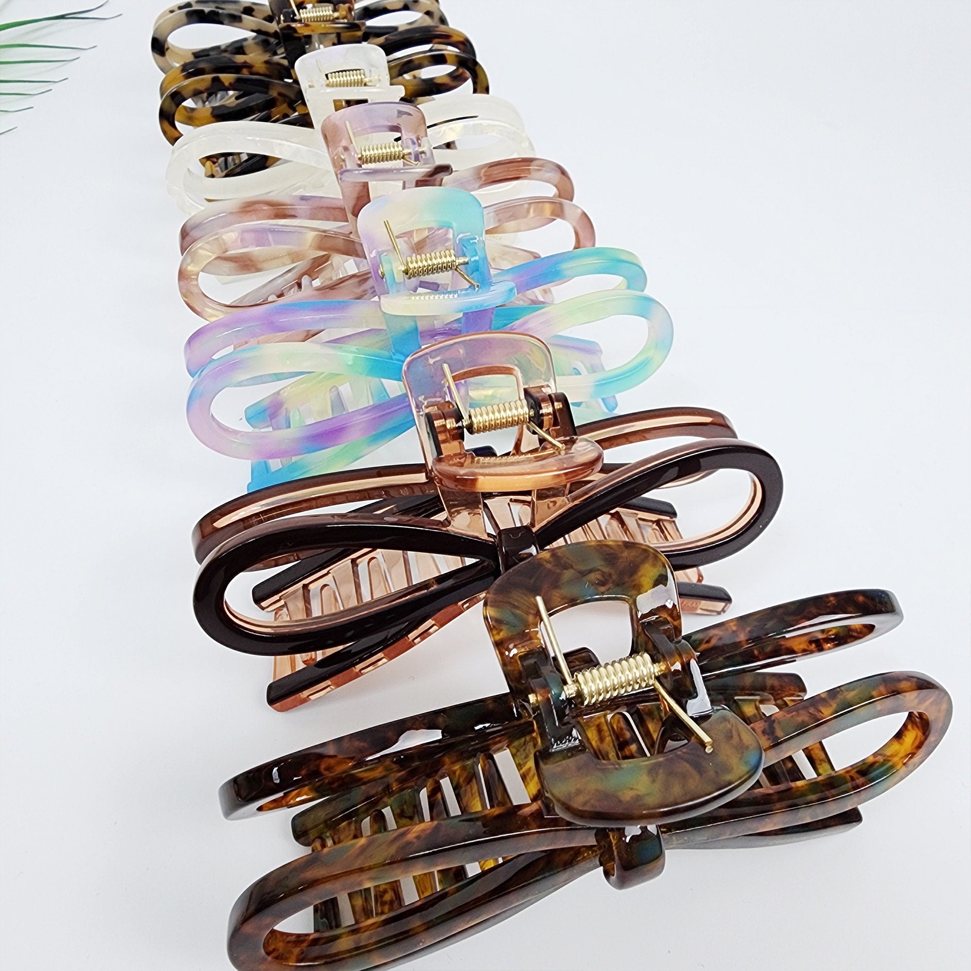 Cellulose acetate bow hair claw in tortoise shell and iridescent marble patterns. Large 4.6 inch ribbon jaw clip for thick hair updo styling and secure grip.