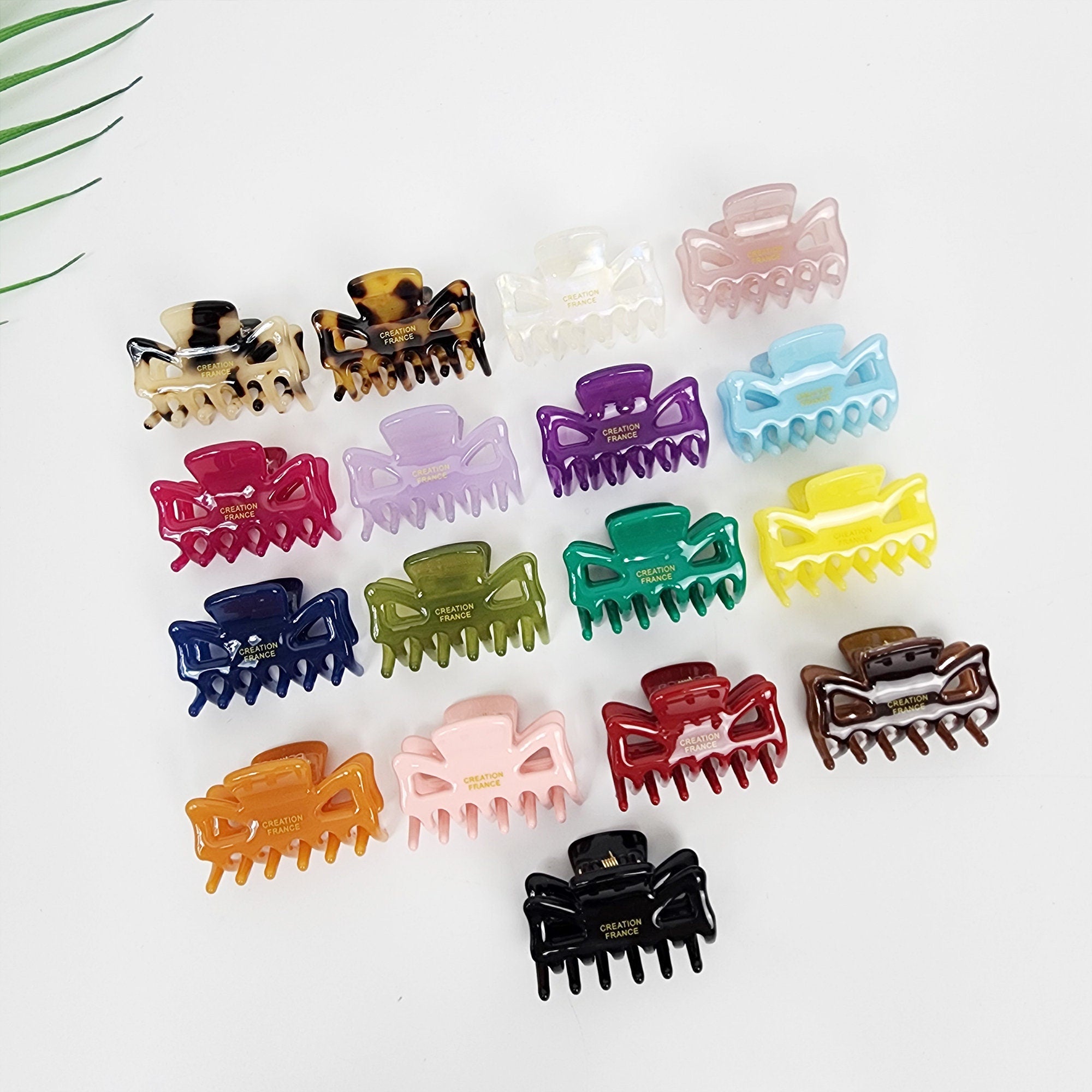 Cellulose acetate mini hair claw clip in masquerade mask shape tortoise and solid colors small jaw clip for side bangs Assortment of colorful plastic hair clips with the words 'Creation France' printed on them. The clips are in various colors including red, green, blue, yellow, orange, purple, brown, black, white, and pink.