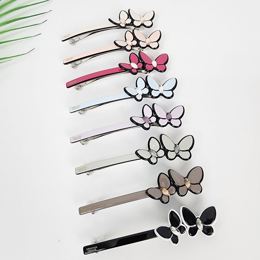 Cellulose acetate slim barrette featuring a double butterfly design with crystal accents. 3.7 inch automatic hair clip ideal for half up styles.