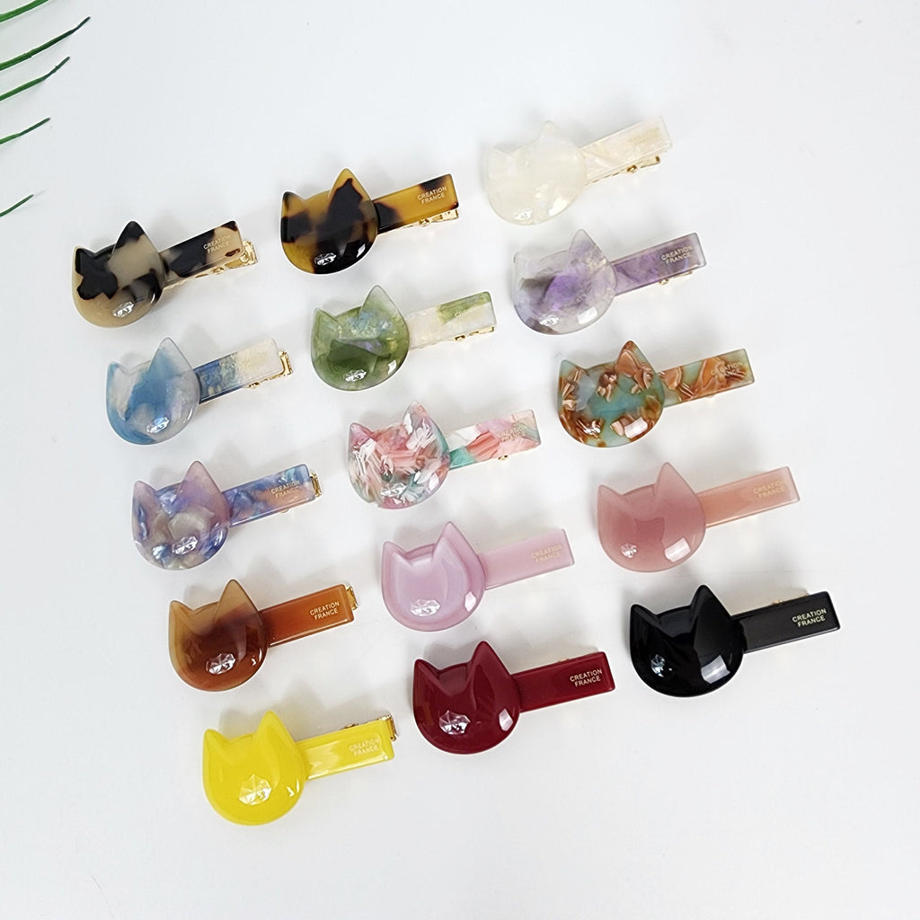 Small cellulose acetate cat shaped hair clip with gold alligator backing for bangs and side hair styling.