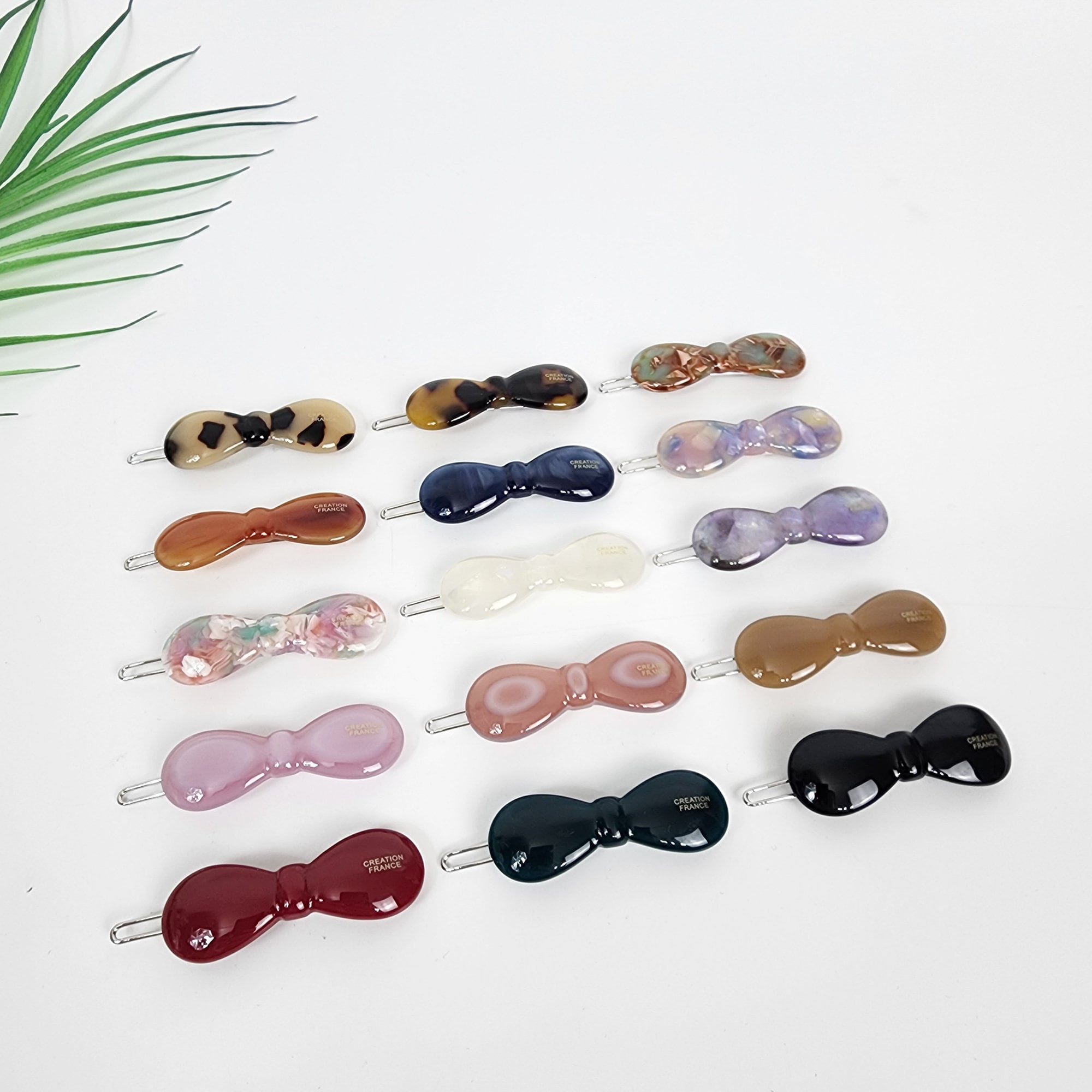 Small cellulose acetate hair clip in a rounded bow shape, available in tortoise shell and pastel colors. Minimalist 1.9-inch snap barrette perfect for holding side bangs or decorating a half-up hairstyle.