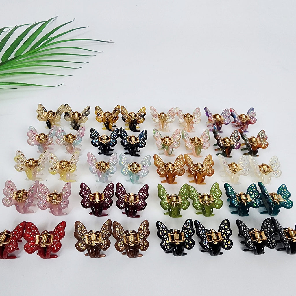 Cellulose acetate mini butterfly hair claw clips sold as a set of 2. Small 0.9 inch rhinestone jaw clips in 20 colors including tortoise shell and glitter, perfect for holding bangs or accenting braids. A collection of 24 butterfly hair clips in various colors including pink, purple, green, blue, brown, gold, and red. The clips are all made of plastic and have a shiny finish. The clips are arranged in rows on a white surface.