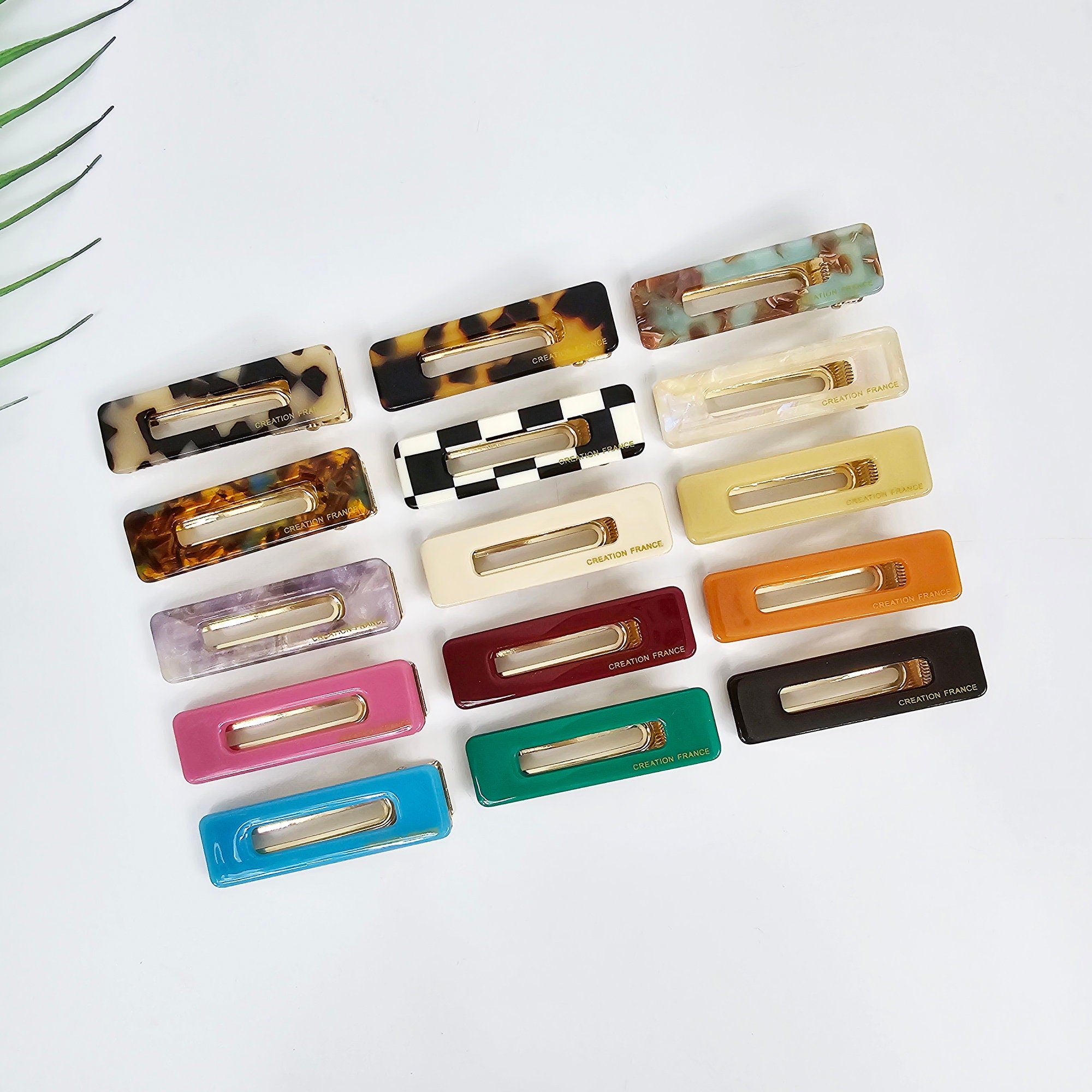 Rectangular cellulose acetate hair clip with open center frame. Small side bangs barrette in tortoise shell and checkerboard patterns for daily styling.