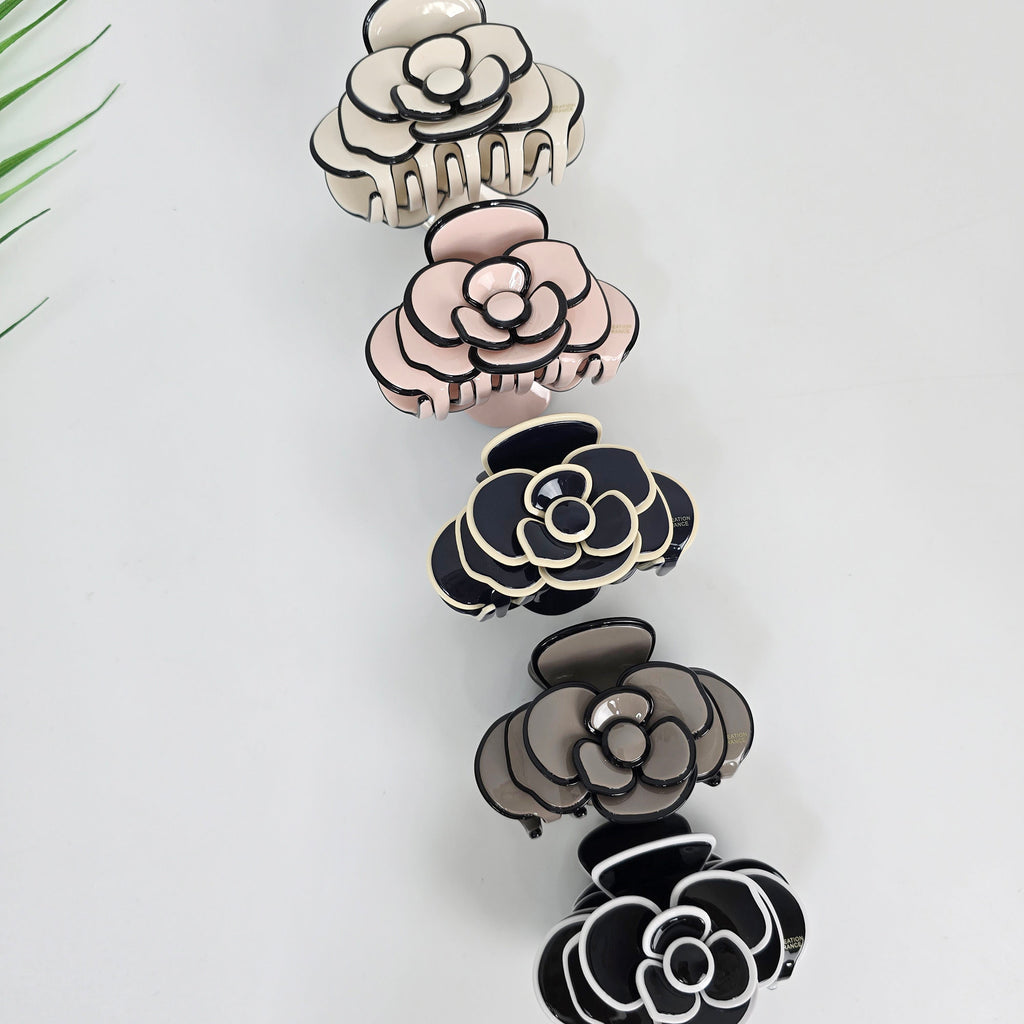 Cellulose acetate hair claw clip shaped like a blooming camellia flower in pastel tones with black outlining. Elegant 3.1 inch floral hair clamp, perfect for romantic half-updos and securing thick hair.