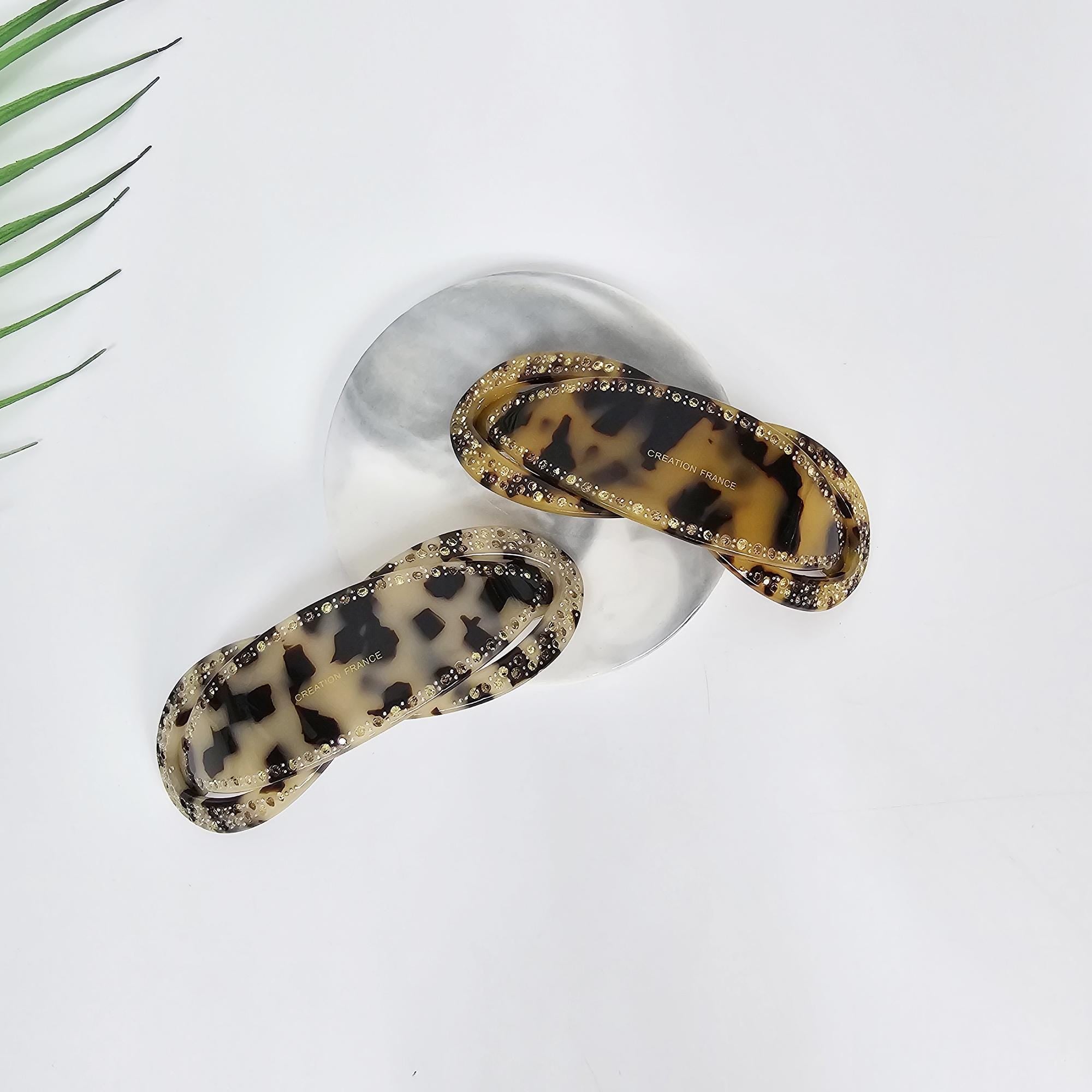 Cellulose Acetate Rhinestone Barrette Tortoise Shell Pattern Automatic Hair Clip for Women Two tortoise shell hair clips with a brown and black leopard print design. The clips are accented with small rhinestones. The text on one clip reads 'CREATION HAUTE'.