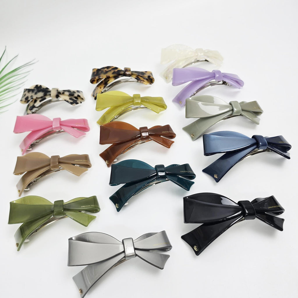 Large cellulose acetate bow barrette featuring a curved glossy finish. 4.1-inch French clip mechanism suitable for half-up styles or ponytails.